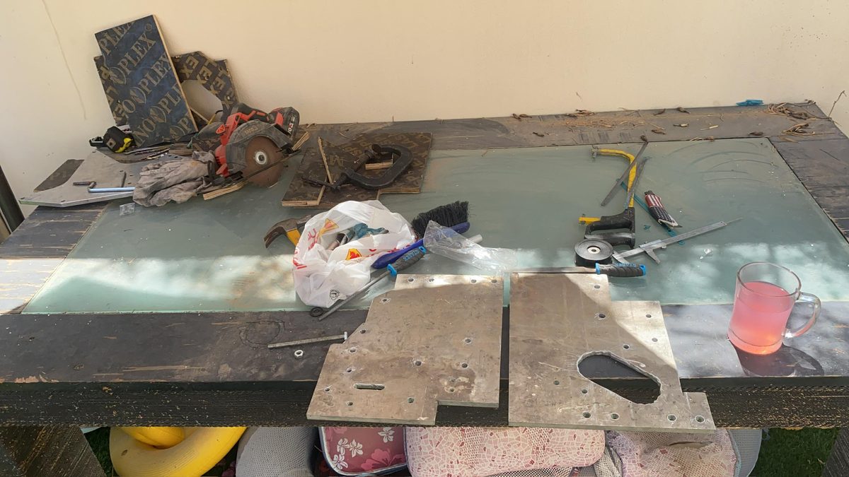 Workbench with circular saw, files, brushes, drill, and aluminum plate cutouts in progress.