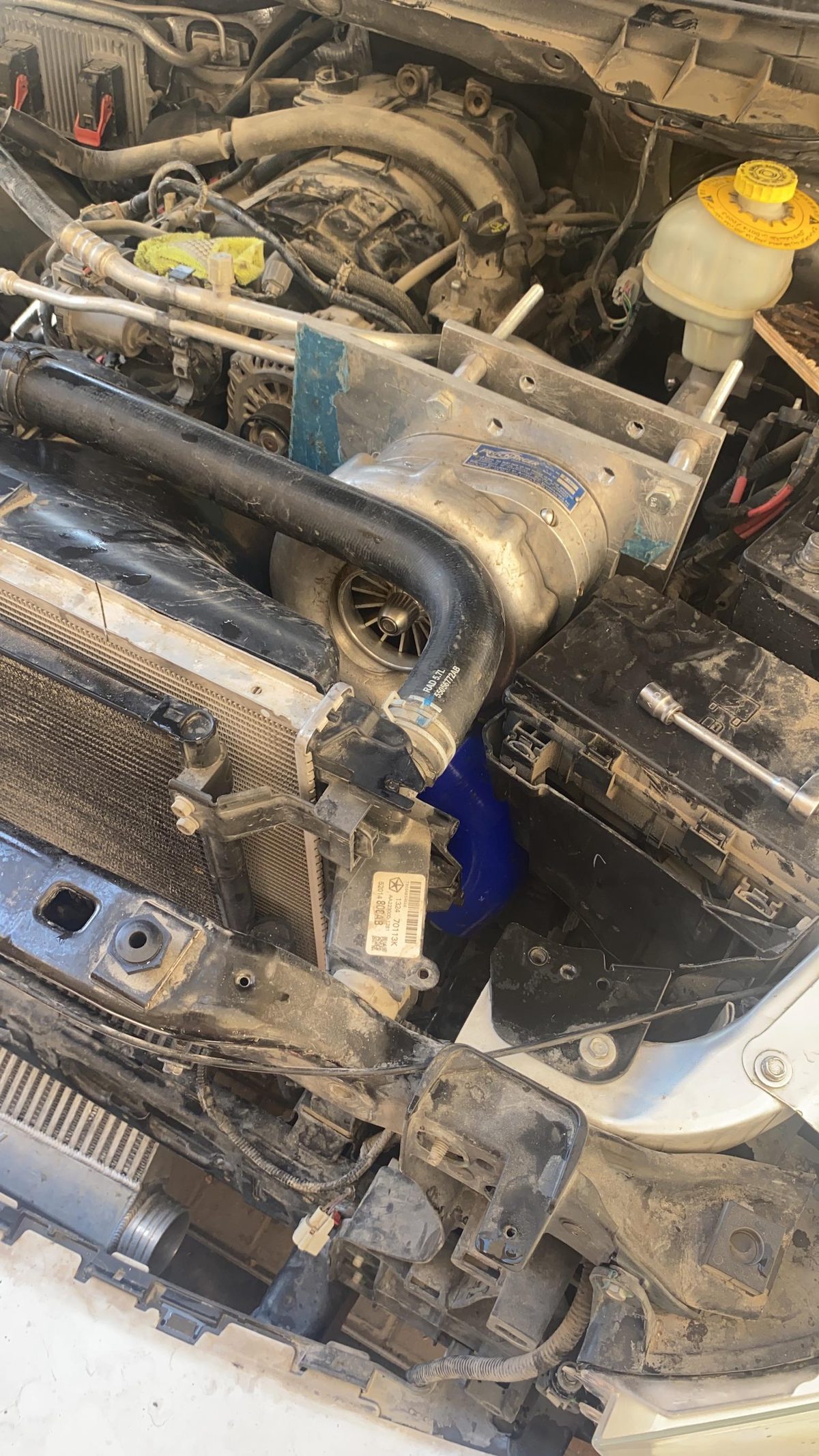 ProCharger mounted in the engine bay of a 2014 RAM 1500 with the blue silicone coupler