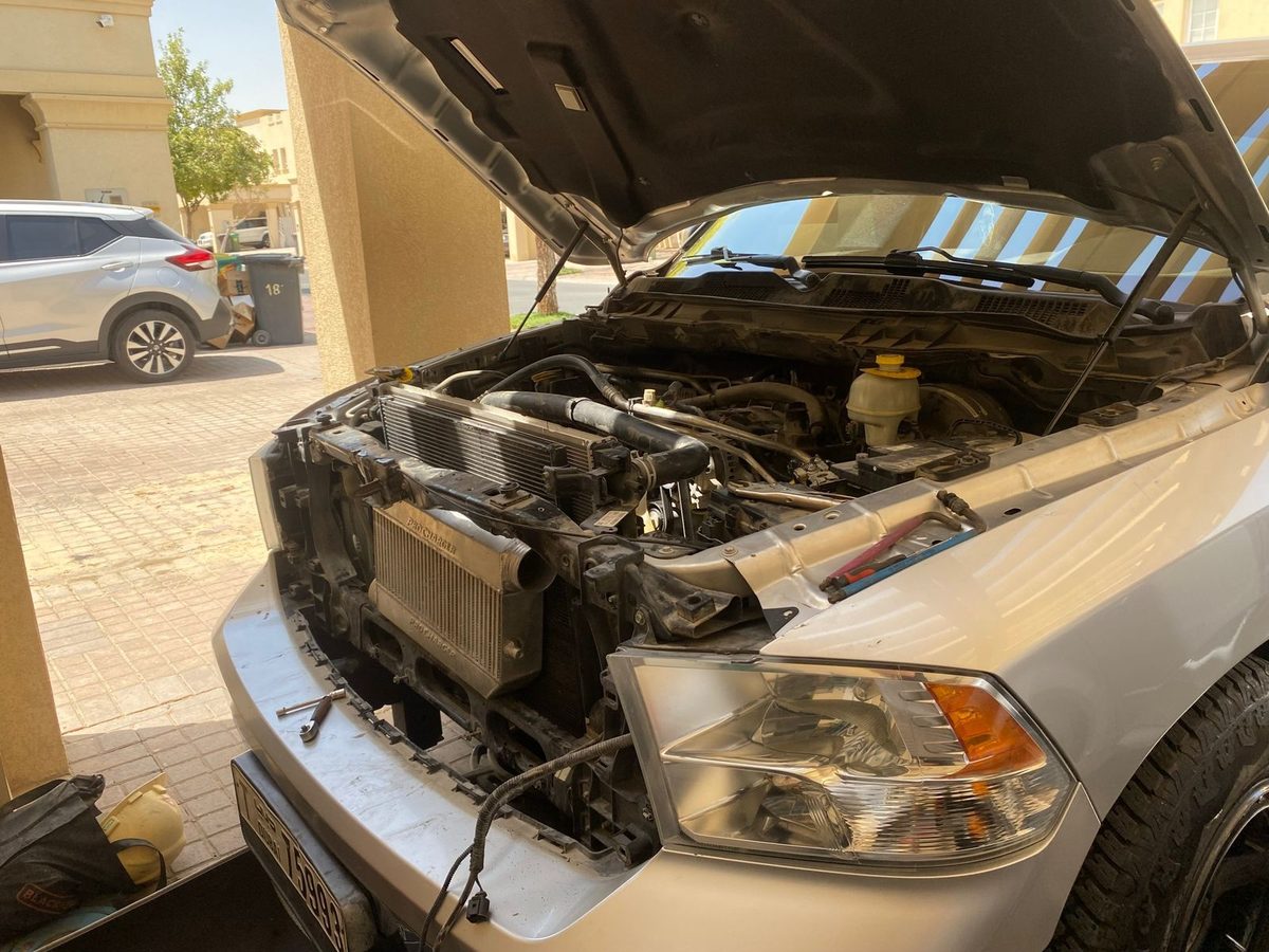 2014 RAM 1500 in the driveway with the hood up. Front grille and intercooler removed for the install.