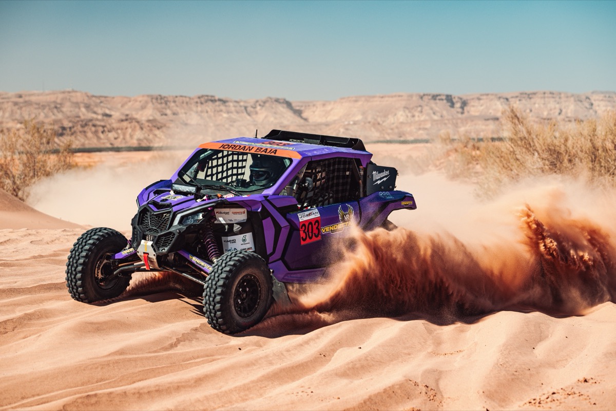 Vendetta Racing UTV #303 sliding head-on through Wadi Rum sand, dust pluming behind it.